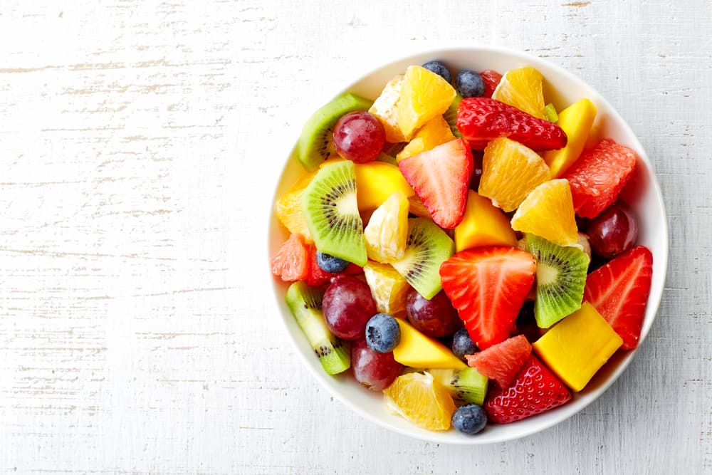 top view of bowl of fruit salad on white background